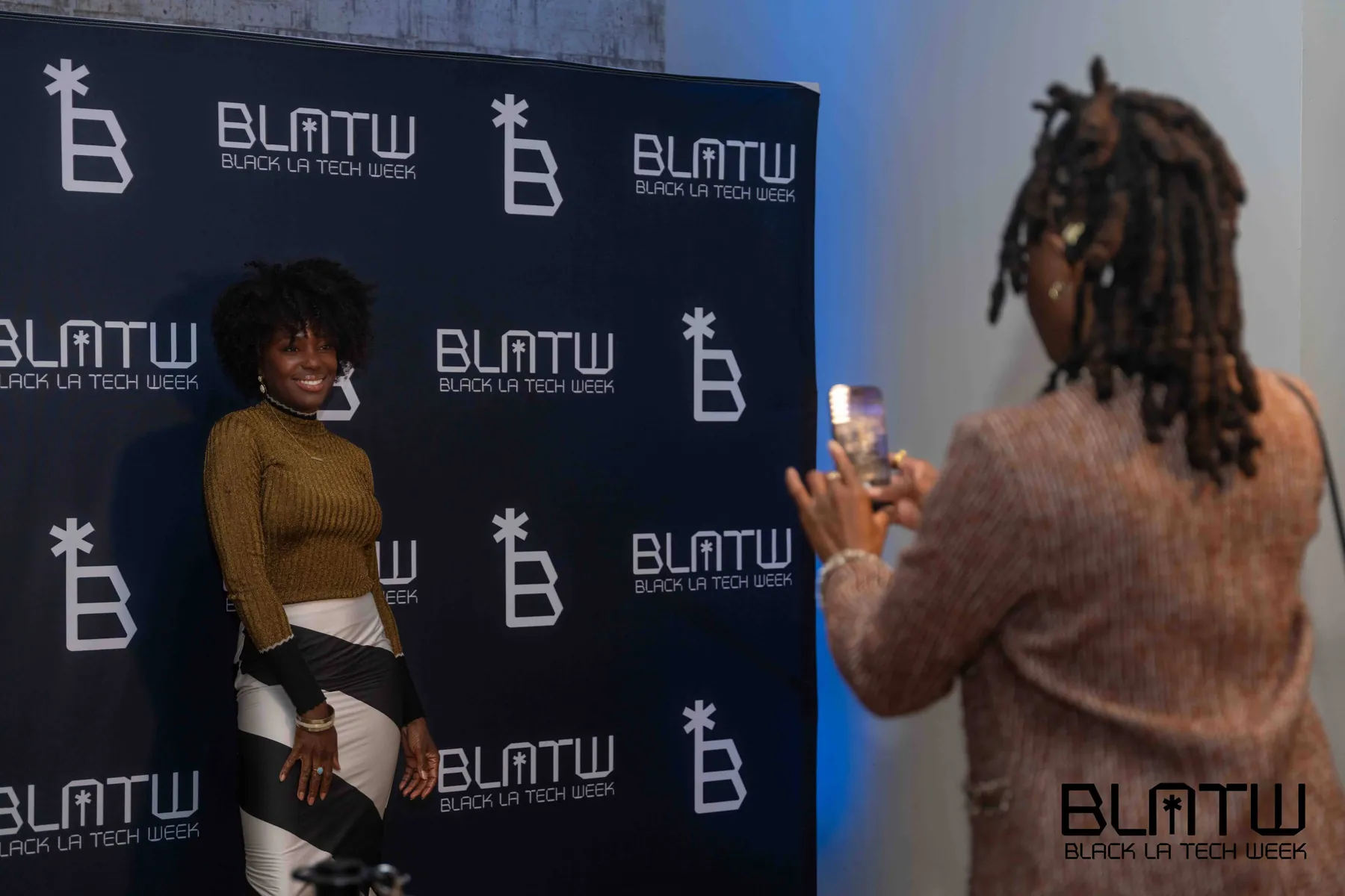 An attendee being photographed in front of the Black L.A. Tech Week backdrop